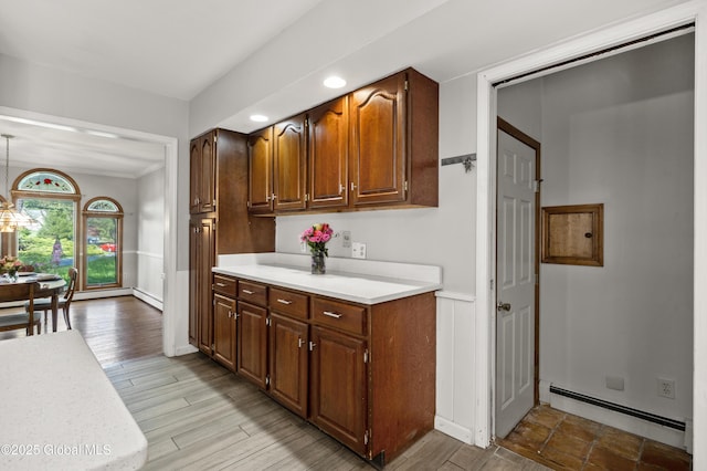 kitchen featuring a baseboard radiator, light countertops, baseboards, wood finished floors, and recessed lighting