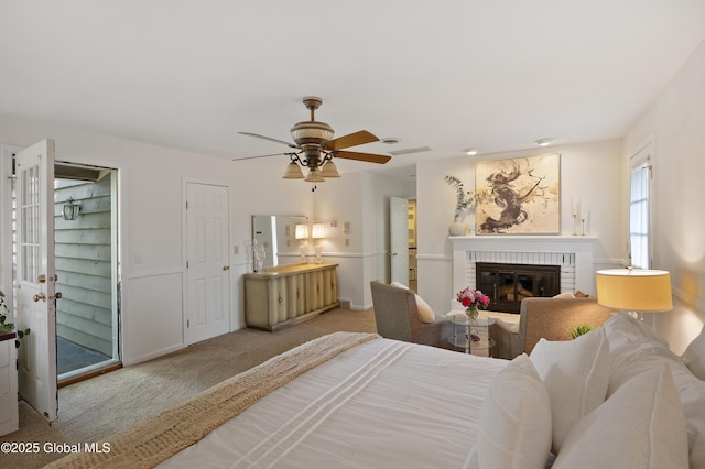 carpeted bedroom with a brick fireplace, baseboards, and ceiling fan