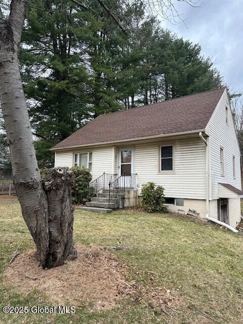 view of front of property featuring a front lawn and roof with shingles