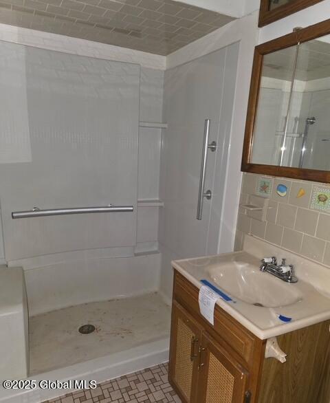 full bathroom with a stall shower, vanity, and tasteful backsplash