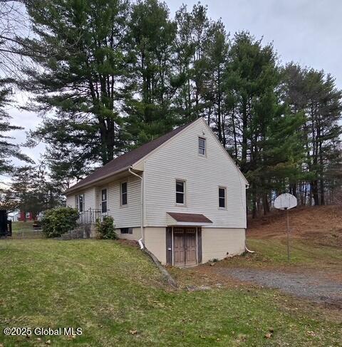 view of side of home featuring a yard and gravel driveway