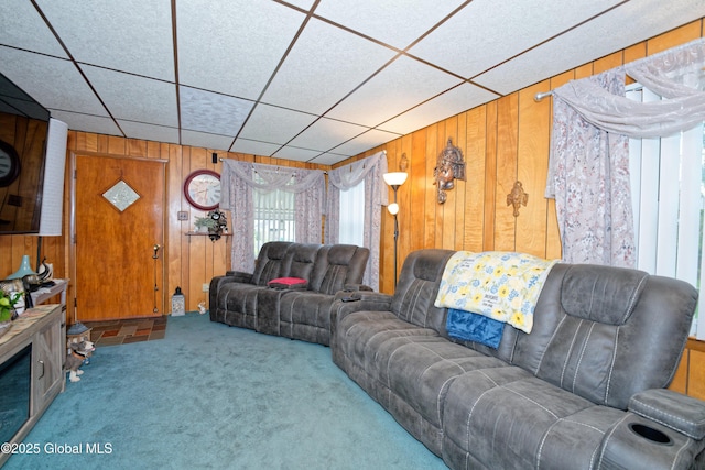 carpeted living room featuring wood walls and a paneled ceiling