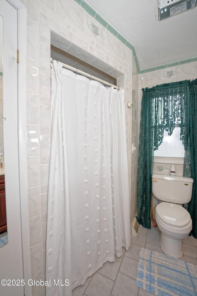 bathroom with tile patterned flooring, tile walls, and toilet