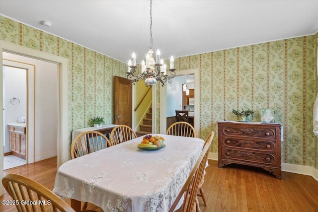 dining room featuring wallpapered walls, hardwood / wood-style floors, a chandelier, stairway, and baseboards