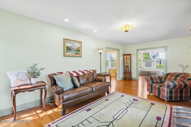 living area with wood finished floors, baseboards, radiator heating unit, and recessed lighting
