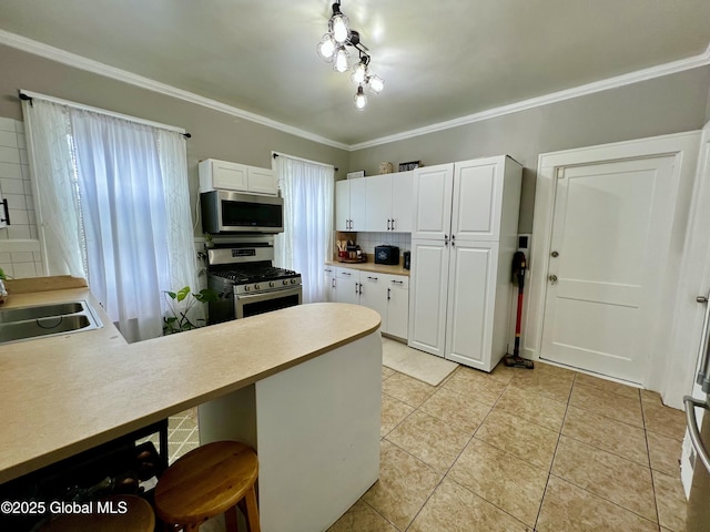 kitchen with stainless steel appliances, healthy amount of natural light, a peninsula, white cabinetry, and ornamental molding