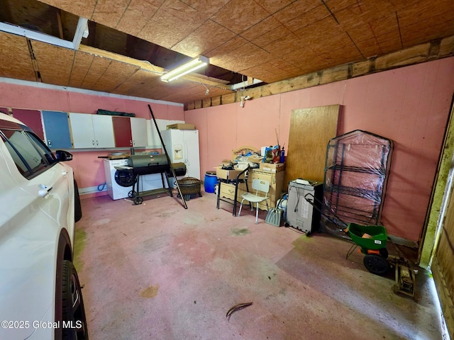below grade area with a garage and white refrigerator with ice dispenser