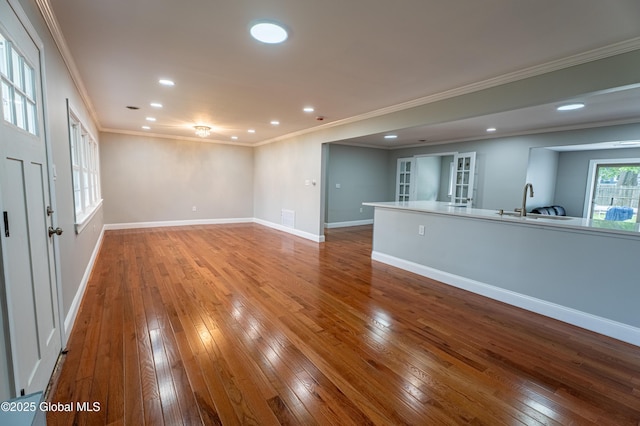 unfurnished living room with hardwood / wood-style flooring, ornamental molding, french doors, recessed lighting, and a sink
