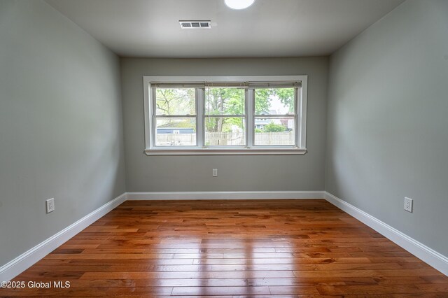 unfurnished room featuring hardwood / wood-style floors and baseboards