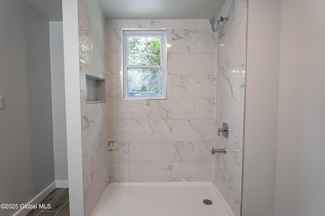 bathroom featuring a tile shower and baseboards