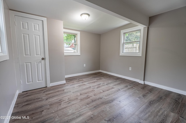 unfurnished bedroom featuring wood finished floors, baseboards, and multiple windows