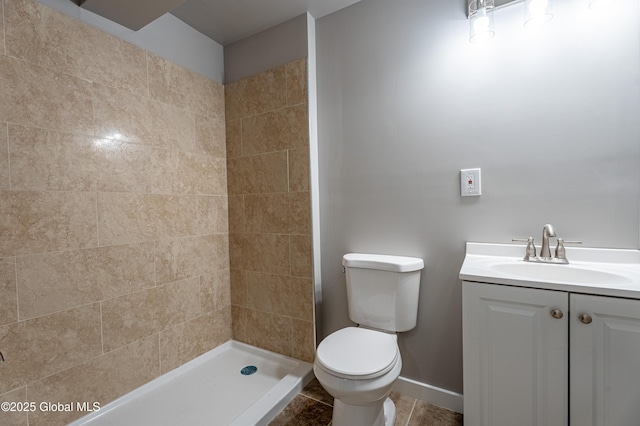 bathroom featuring toilet, a stall shower, vanity, tile patterned floors, and baseboards