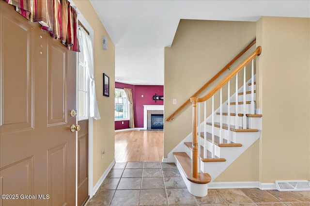 entryway with a fireplace, stairs, and baseboards