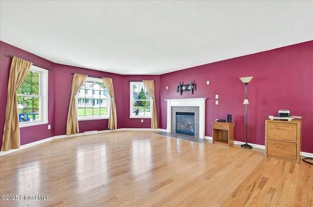unfurnished living room with a fireplace, light wood finished floors, and baseboards