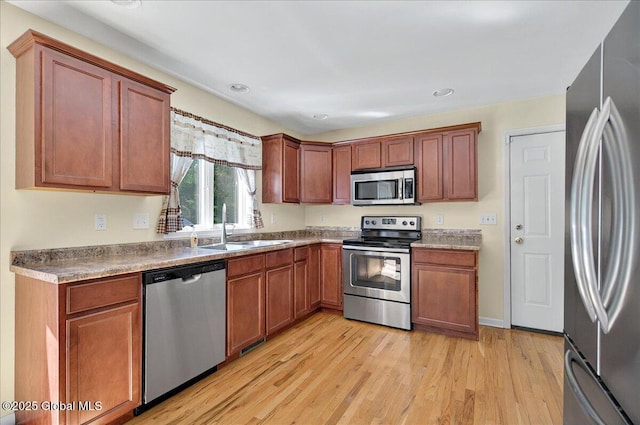 kitchen with stainless steel appliances, a sink, light wood-style flooring, recessed lighting, and brown cabinets