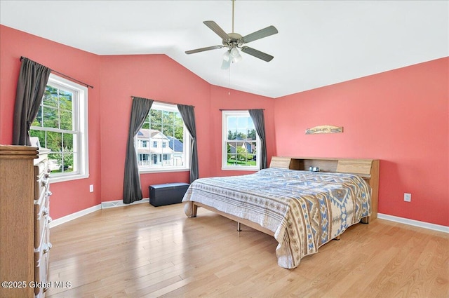 bedroom featuring wood finished floors, lofted ceiling, baseboards, and ceiling fan