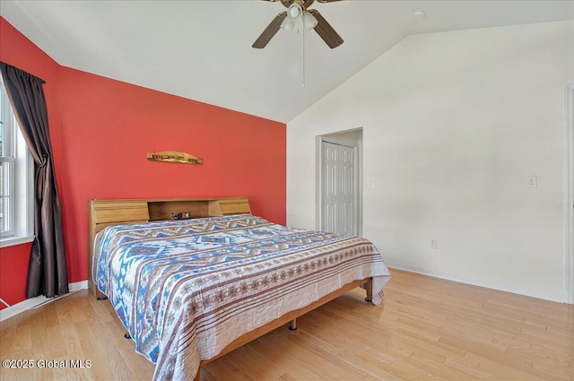 bedroom featuring wood finished floors, high vaulted ceiling, baseboards, and a ceiling fan