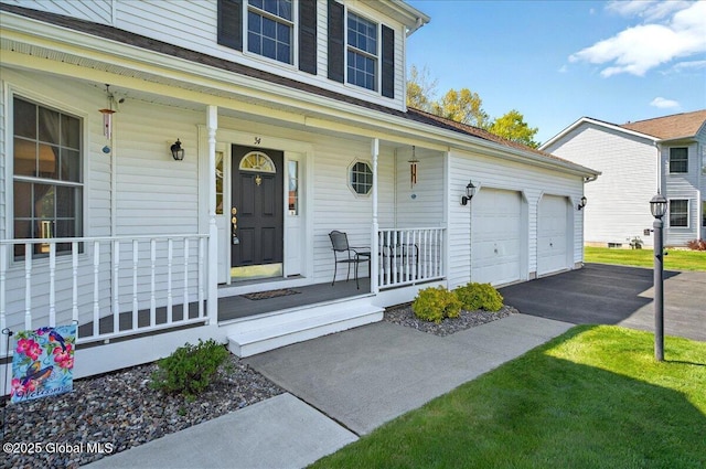 entrance to property featuring a porch, driveway, and an attached garage