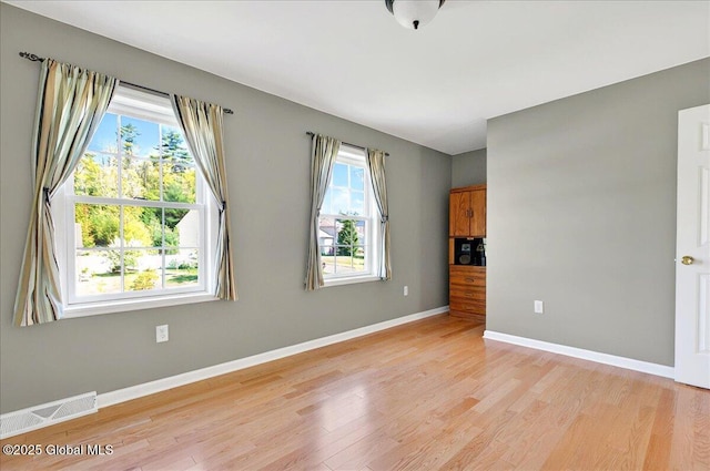 spare room featuring light wood-style flooring, healthy amount of natural light, and baseboards