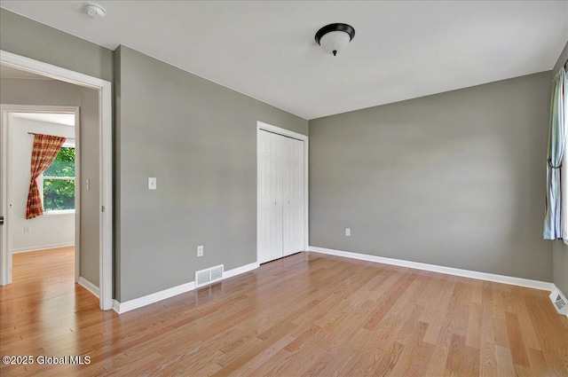 unfurnished bedroom featuring light wood finished floors, baseboards, and a closet