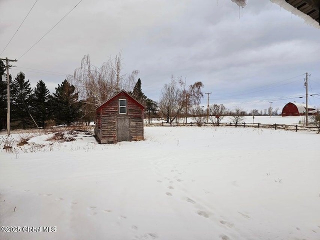 yard layered in snow with a storage unit and an outbuilding