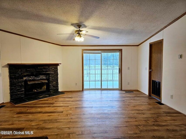 unfurnished living room with ornamental molding, wood finished floors, ceiling fan, a stone fireplace, and a textured ceiling
