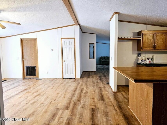 interior space featuring light wood-style flooring, a ceiling fan, ornamental molding, and a textured ceiling
