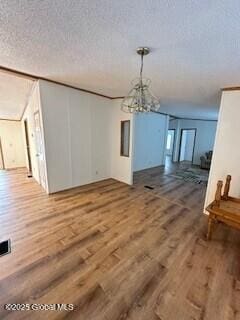 unfurnished dining area with wood finished floors, a chandelier, and a textured ceiling