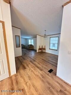 bonus room featuring wood finished floors, a textured ceiling, and a chandelier