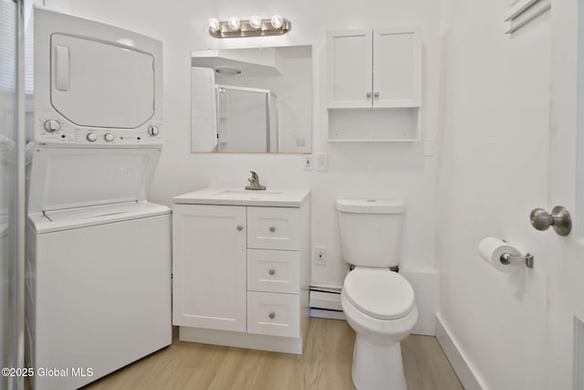 821 7th St, Rensselaer, NY 12144 - full bath with stacked washer / drying machine, wood finished floors, toilet, baseboard heating, and vanity