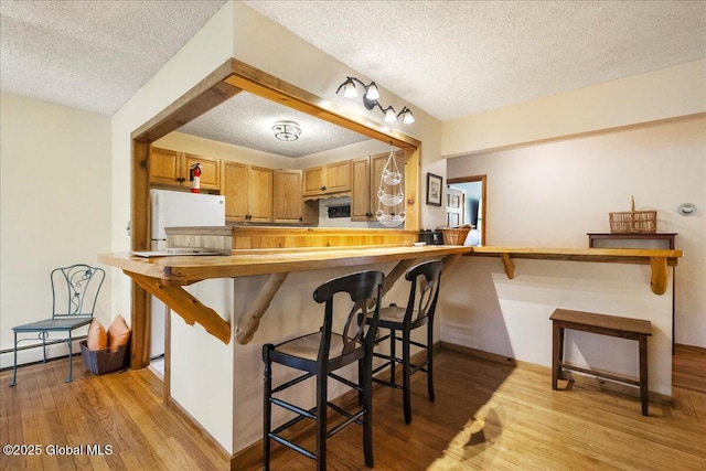 1 High Pines Ter Unit 1C, Chester, NY 12817 - kitchen featuring a textured ceiling, light wood-type flooring, a baseboard heating unit, a peninsula, and a breakfast bar area