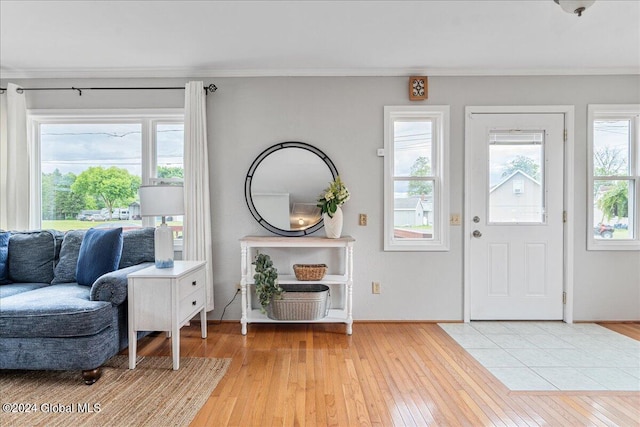 foyer entrance with plenty of natural light, light wood-style floors, crown molding, and baseboards