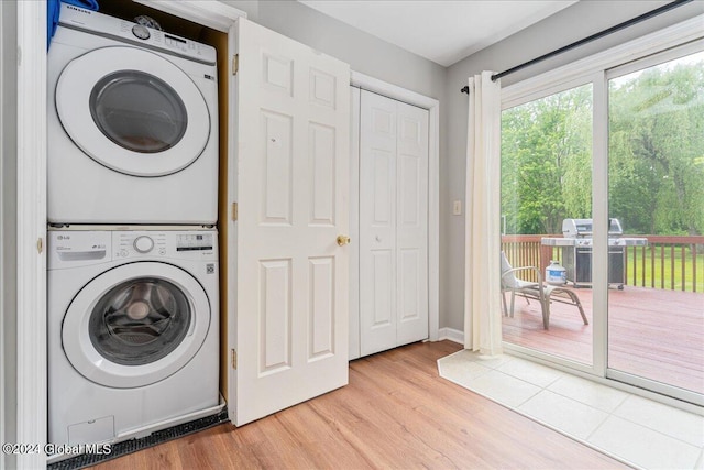 clothes washing area with stacked washer and clothes dryer, wood finished floors, and baseboards