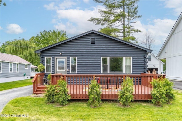 back of house with log siding, a yard, and a wooden deck