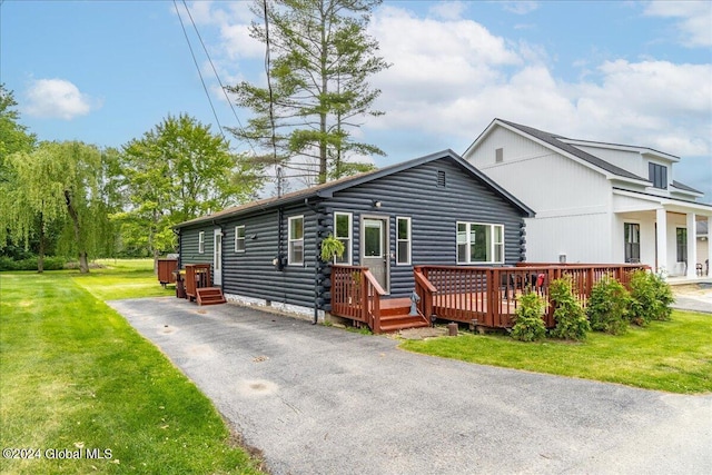 view of front of property with log exterior, asphalt driveway, a front lawn, and a wooden deck
