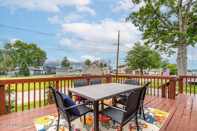 wooden terrace featuring a residential view, outdoor dining space, and a lawn