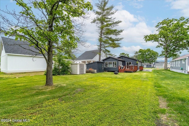 view of green lawn with a storage unit, an outdoor structure, and a wooden deck