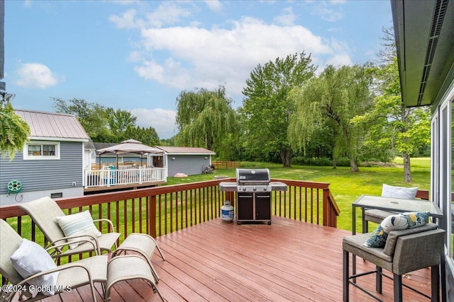 wooden terrace with area for grilling, a yard, and view of wooded area