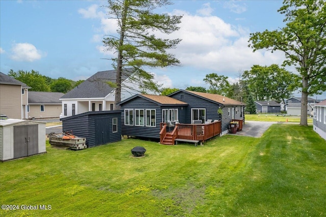 back of house with a shed, an outbuilding, a wooden deck, and a yard