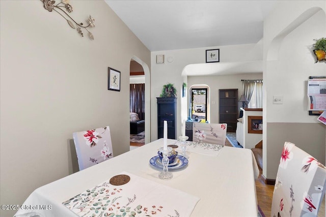 dining area with arched walkways and wood finished floors