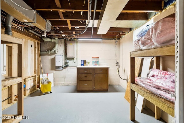 unfinished basement featuring electric panel and concrete block wall