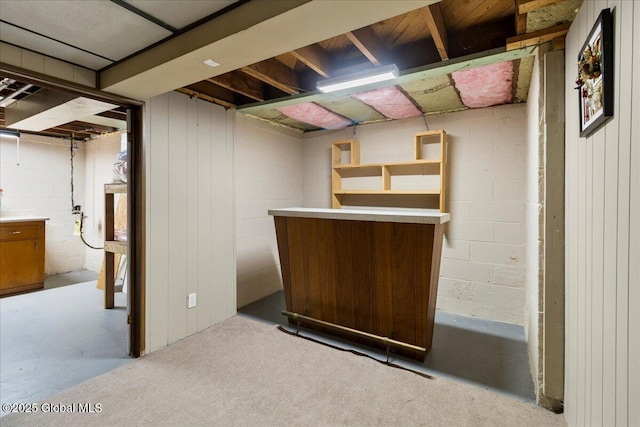 finished basement with a dry bar and concrete block wall