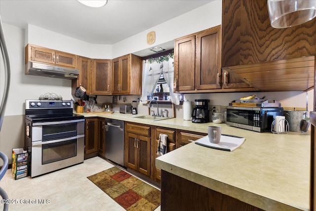 kitchen featuring stainless steel appliances, under cabinet range hood, a sink, and light countertops