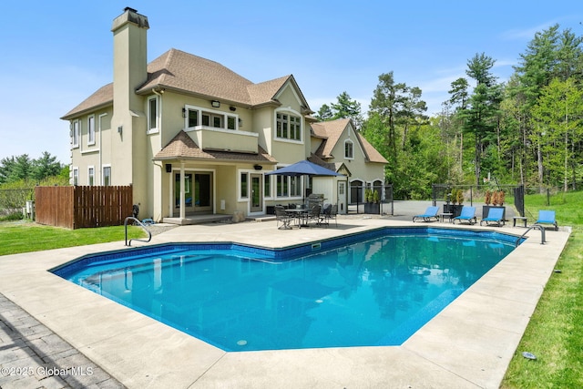 back of property featuring a chimney, a patio, and stucco siding
