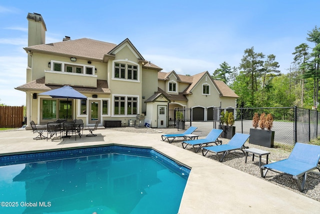 back of house with fence, a patio, stucco siding, and a chimney