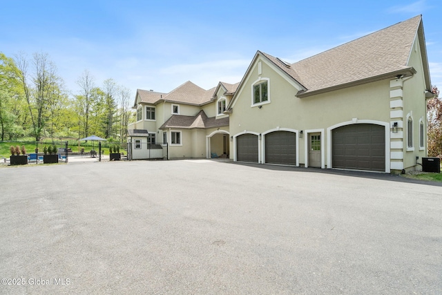 view of front of house with fence, an attached garage, stucco siding, driveway, and a shingled roof