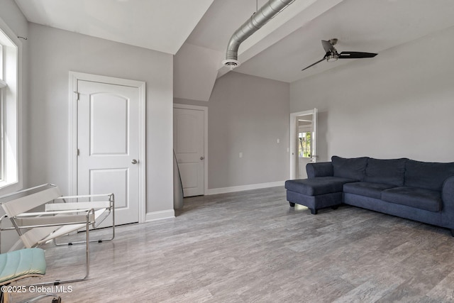 living room featuring ceiling fan, light wood-style floors, and baseboards