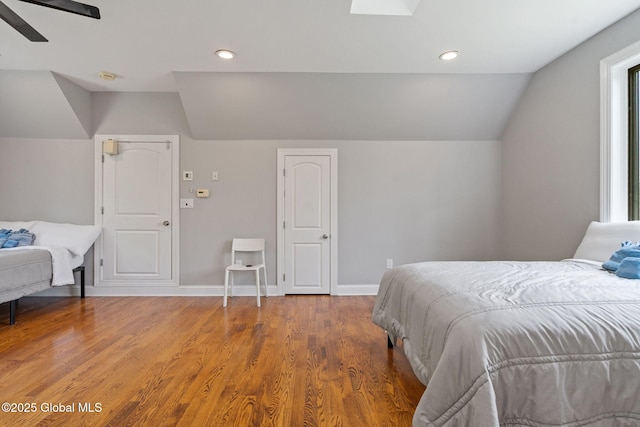 bedroom featuring lofted ceiling, wood finished floors, baseboards, recessed lighting, and a ceiling fan