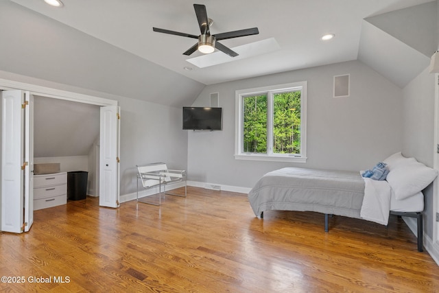 bedroom with vaulted ceiling, a skylight, light wood-style flooring, ceiling fan, and recessed lighting