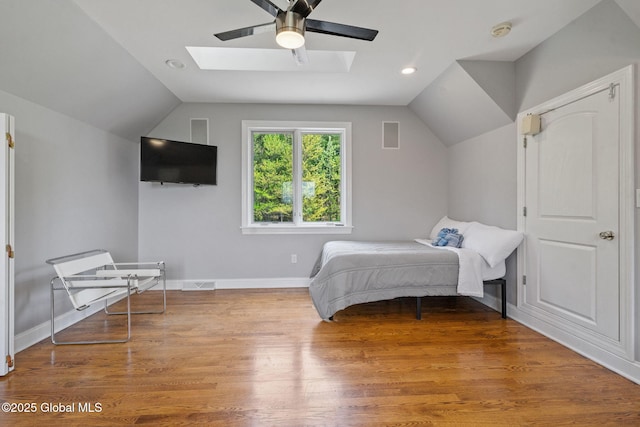 bedroom with lofted ceiling, a skylight, baseboards, a ceiling fan, and wood finished floors